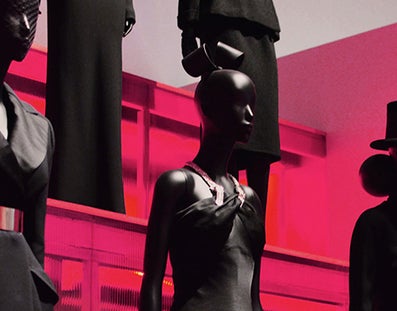 Mannequins dressed in black with a red lit background.