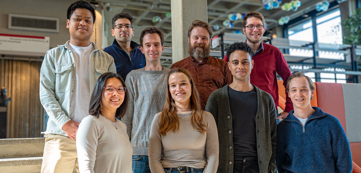 A group photo of the VU Education Analytics team. Smiling, they look into the camera as they pose in an informal setting in the main building of Vrije Universiteit Amsterdam.