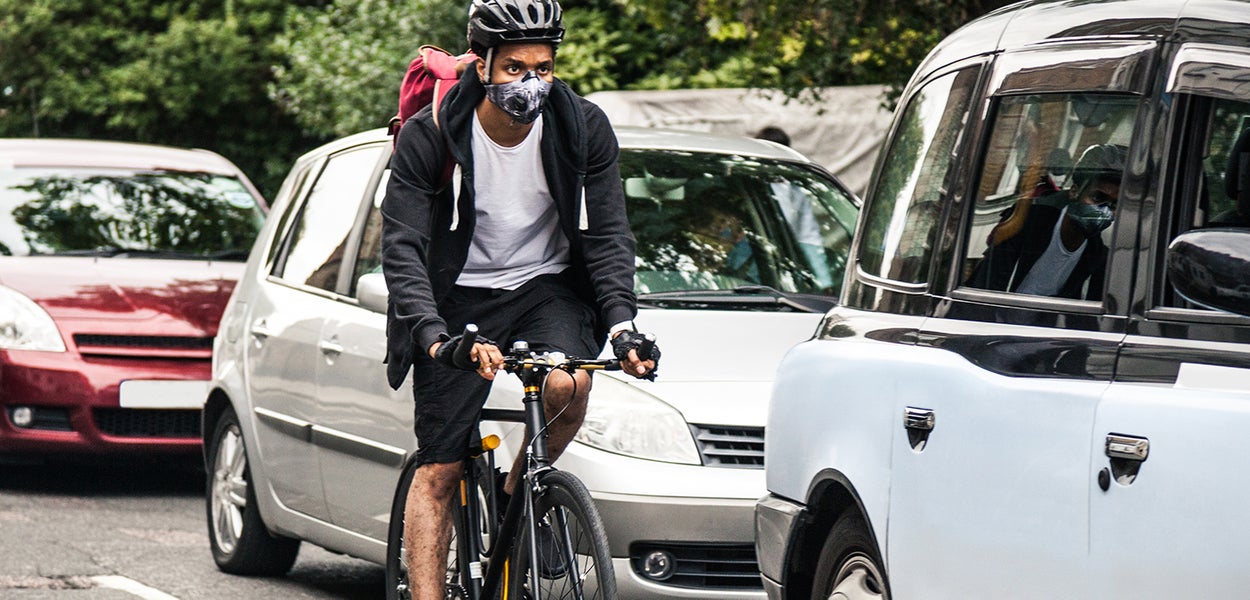 Fietser fietst met een mondkapje op naast auto's 