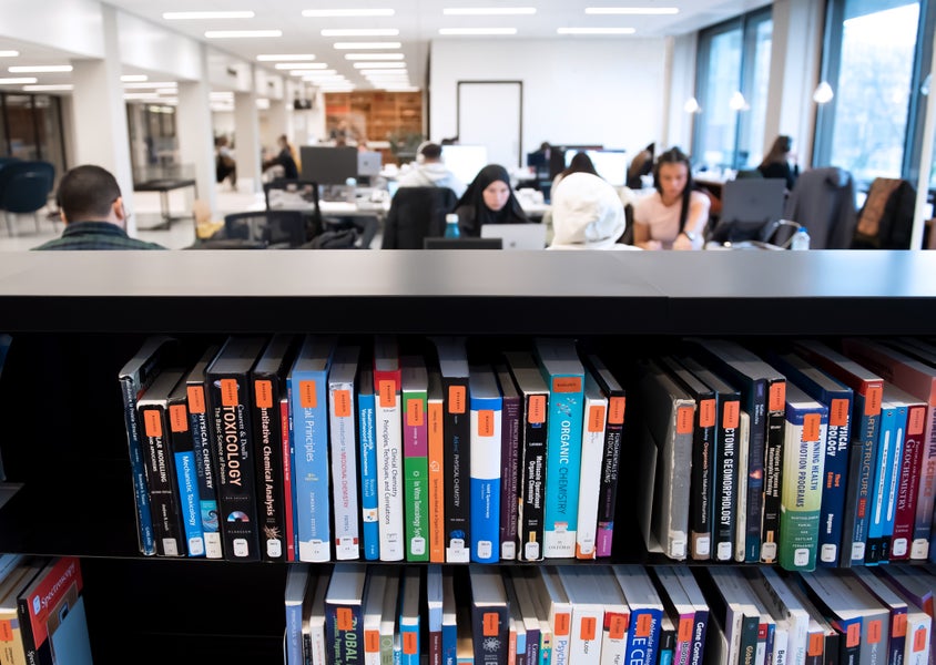 Studenten studeren in studiezaal van de Universiteitsbibliotheek. Vooraan staan boeken voor de daguitleen. Foto: Monique Kooijmans