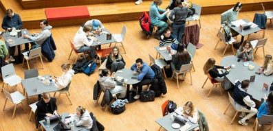 Overhead view of students at tables in the atrium of the New University Building
