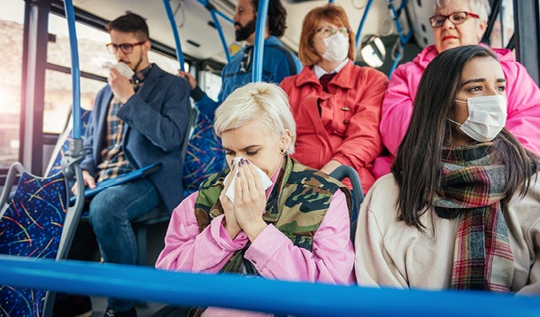 People wearing masks in public transport, one of them is blowing her nose