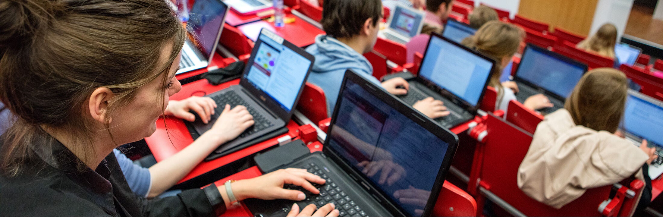 Studenten achter hun laptops in een collegezaal