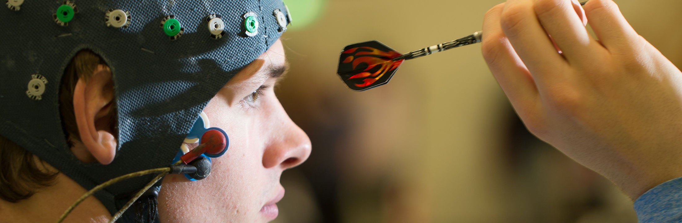 Een jongen met een muts met elektroden op zijn hoofd is aan het darten