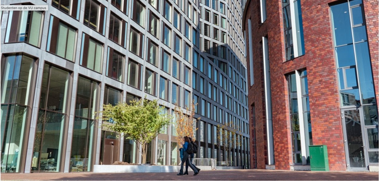 
Twee studenten lopen voorbij een modern universiteitsgebouw met grote glazen ramen.