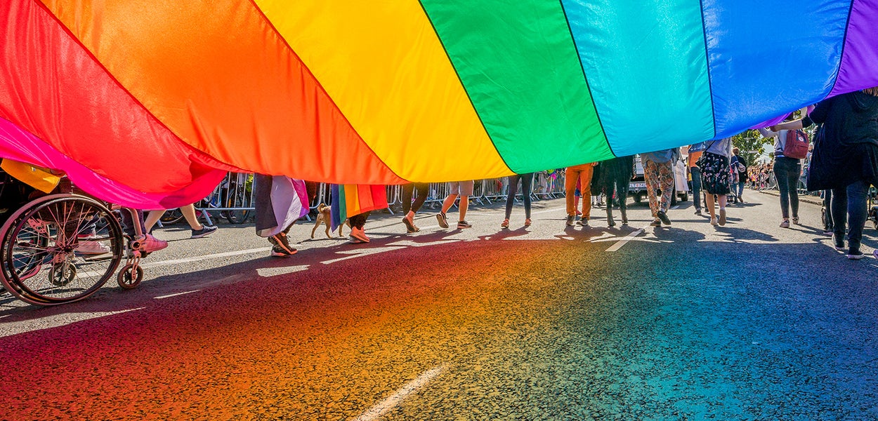 Deelnemers van de Pride Walk dragen de regenboogvlag op straat