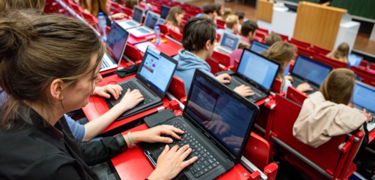 Een klaslokaal vol studenten die aantekeningen maken op hun laptops.