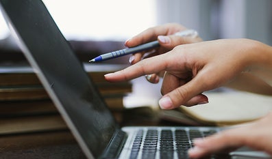 Twee handen die wijzen naar het scherm van een laptop