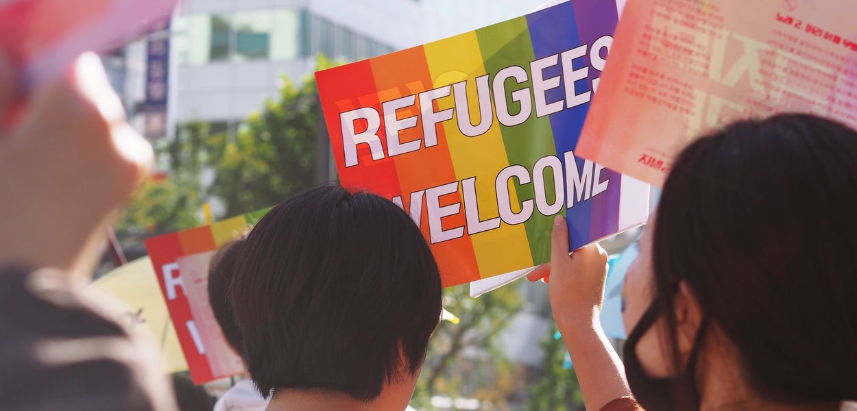 Persoon met een pamflet in diens handen waarop "Refugees Welcome" staat