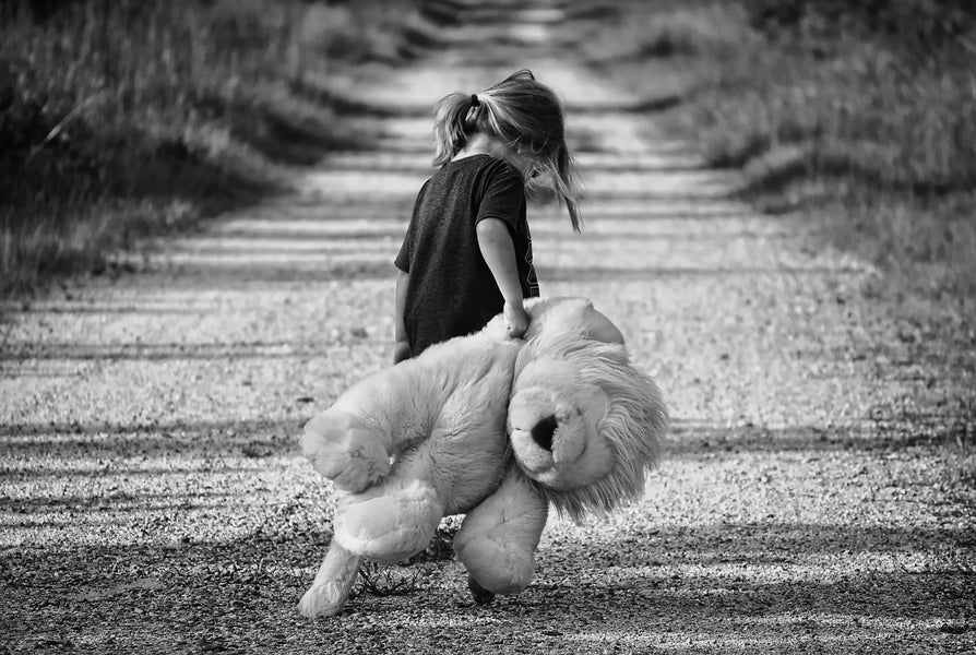 Meisje met grote speelgoedbeer eenzaam op landweg