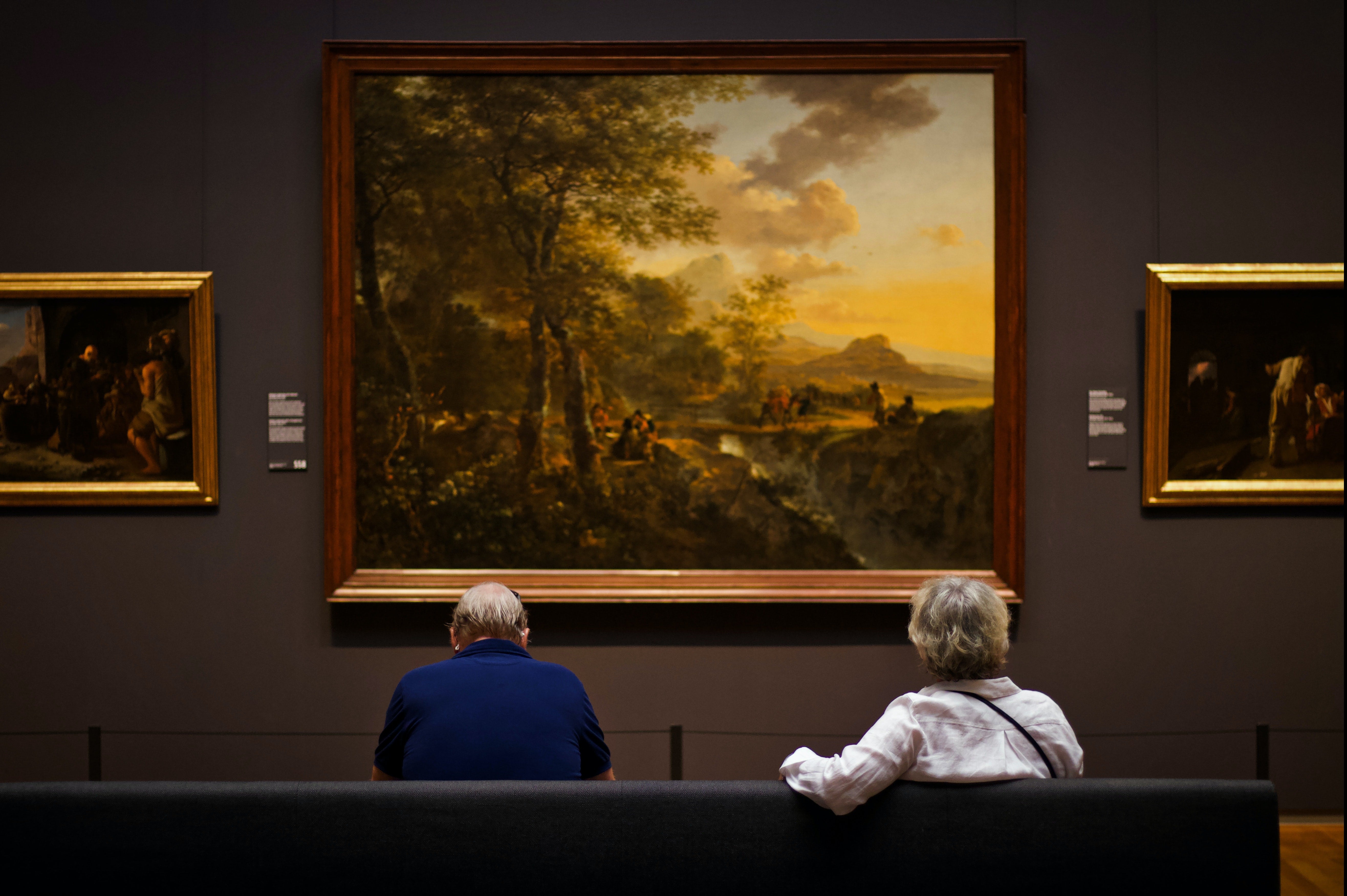 Mensen kijken naar een schilderij in een museum.