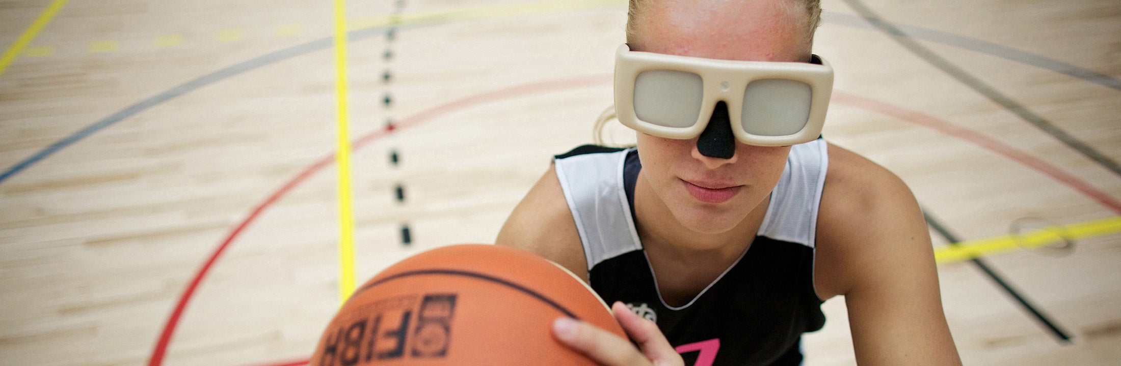 Een meisje speelt basketbal met een speciale bril op