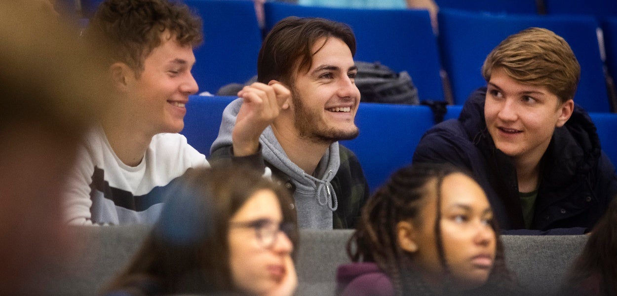Studenten lachen en praten met elkaar tijdens een college.