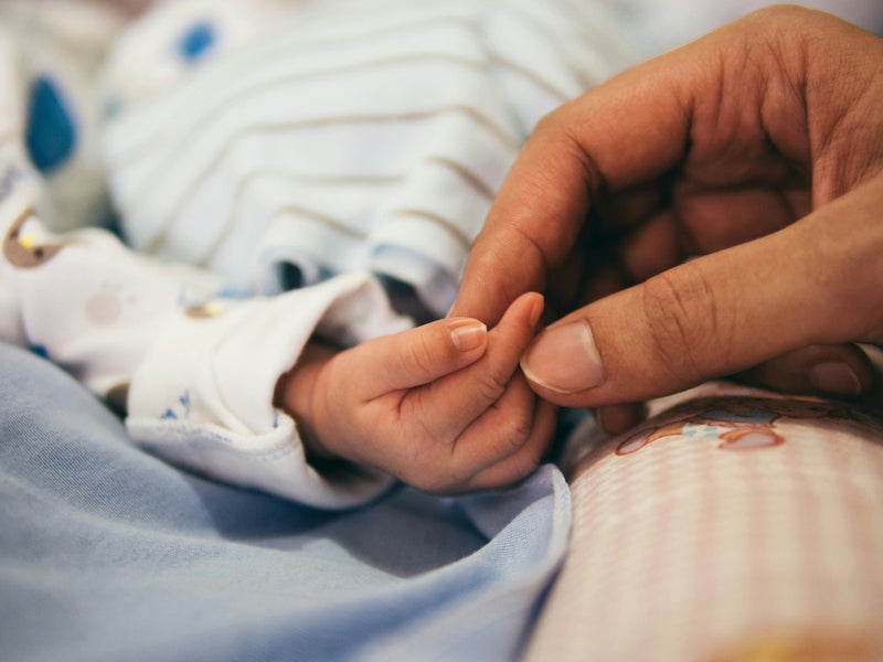 Een ouder houdt de hand vast van een pasgeboren baby