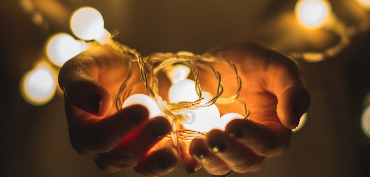 Op de foto is een close up te zien van een persoon die in zijn handen een lichtsnoer dat licht geeft, vasthoudt. Foto dank aan Josh Boot op Unsplash. 
