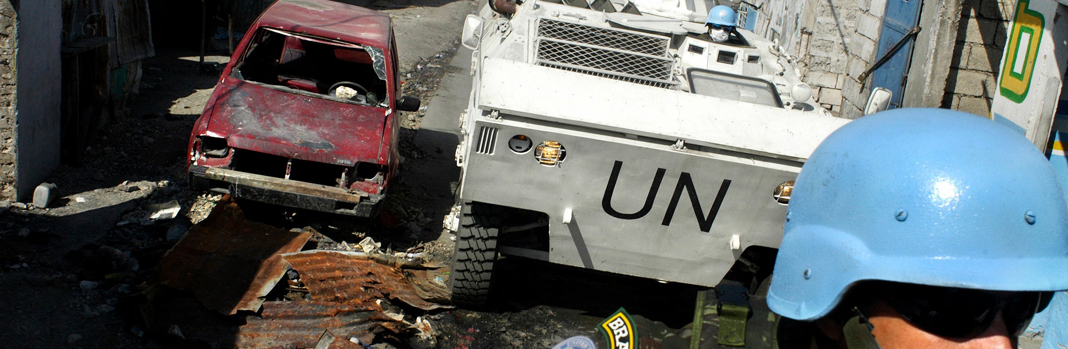 Een blauwhelm soldaat kijkt richting rijdende VN tank