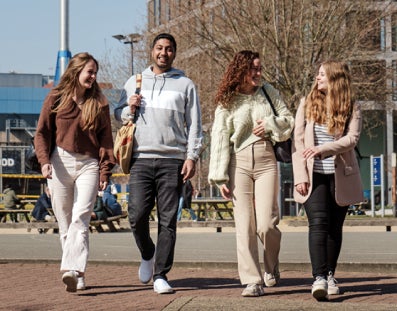 Four students walking on the VU campus square