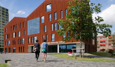 Twee studenten lopen naar de entree van het gebouw van Amsterdam University College