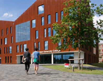 Twee studenten lopen naar de entree van het gebouw van Amsterdam University College