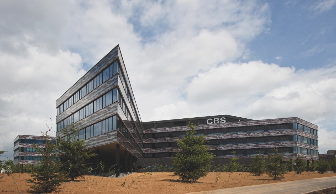 he CBS building surrounded by sand, trees and a cloudy sky