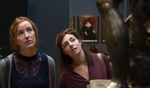 2 jonge vrouwen kijken geïnteresseerd naar een kunstwerk