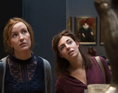 2 jonge vrouwen kijken geïnteresseerd naar een kunstwerk